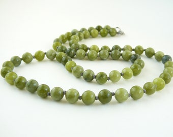 Puede incluir: Un collar de cuentas de jade verde con nudos de cuerda gris entre cada cuenta.