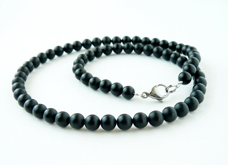 May include: A black beaded necklace with a silver clasp. The beads are round and matte.