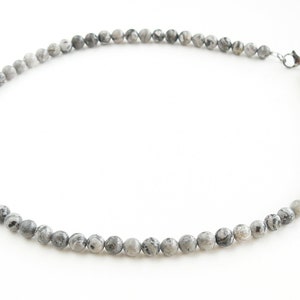 May include: A gray and white stone bead necklace with a silver clasp.