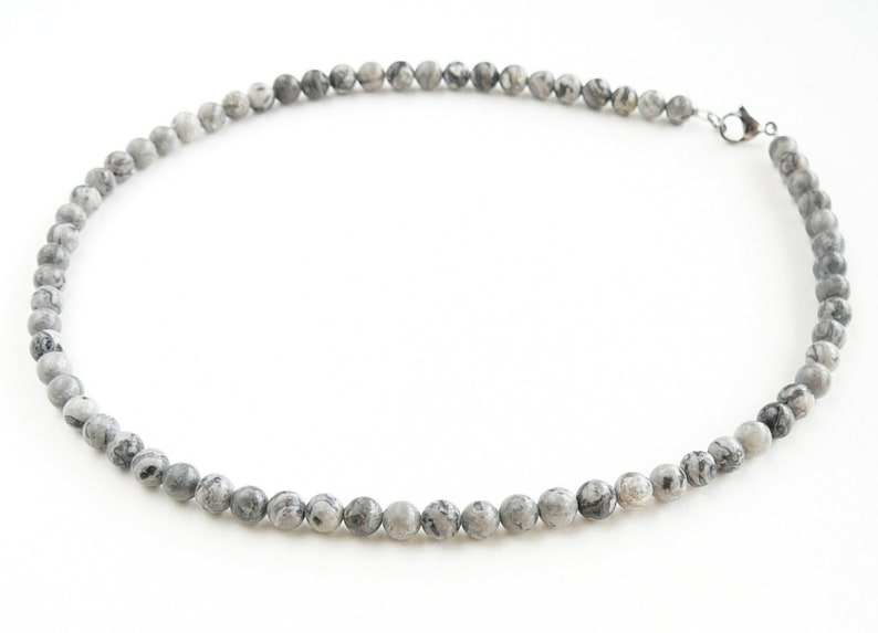 May include: A gray and white stone bead necklace with a silver clasp.