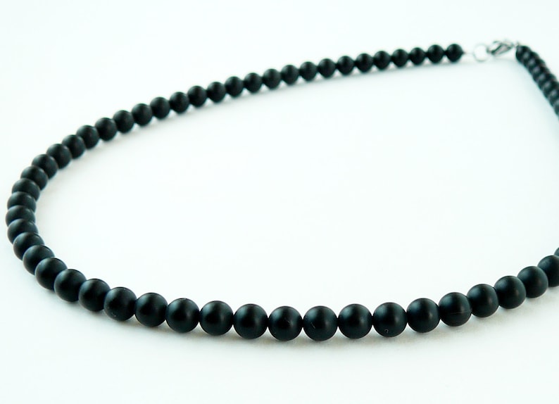 May include: A black beaded necklace with a silver clasp. The beads are round and matte.