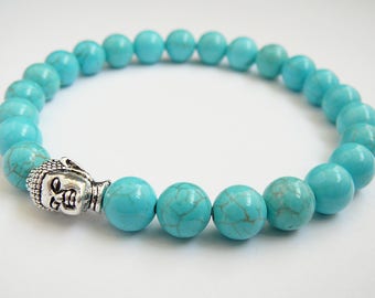 May include: Turquoise blue beaded bracelet with a silver Buddha head charm.