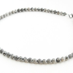 May include: A gray and white stone bead necklace with a silver clasp.