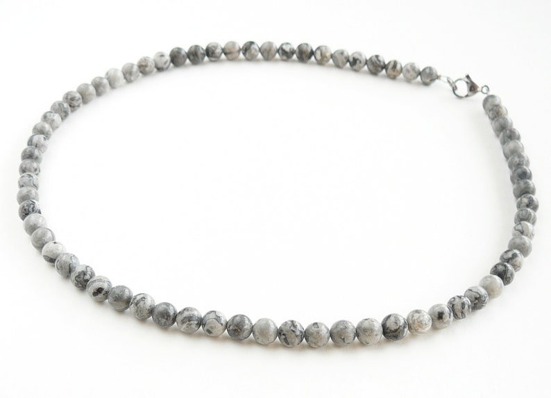 May include: A gray and white stone bead necklace with a silver clasp.