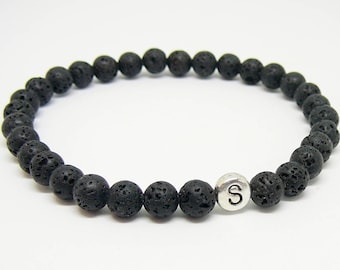 May include: Black lava rock beaded bracelet with a silver charm bead featuring the letter "S".