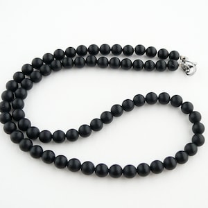 May include: A black beaded necklace with a silver clasp. The beads are round and matte.