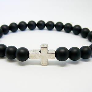 May include: A black beaded bracelet with a silver cross charm.