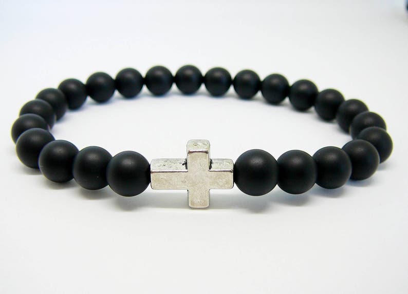 May include: A black beaded bracelet with a silver cross charm.