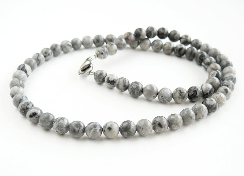 May include: A gray and black marbled stone beaded necklace with a silver clasp.