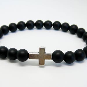 May include: A black beaded bracelet with a silver cross charm.
