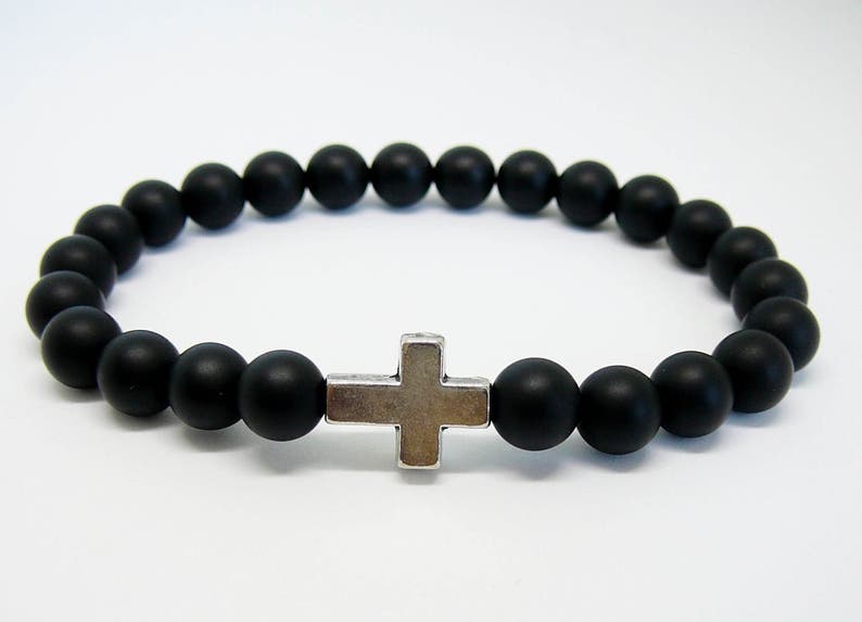 May include: A black beaded bracelet with a silver cross charm.