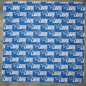 Puede incluir: Un pañuelo azul con un patrón blanco repetido del logotipo de los Detroit Lions. El logotipo presenta un león con las palabras "Detroit Lions" debajo.