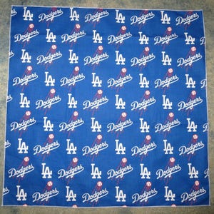 Könnte beinhalten: Ein blaues Bandana mit einem sich wiederholenden Muster aus weißen "LA Dodgers"-Logos. Die Logos sind in einem Raster angeordnet und zeigen einen Baseball und ein stilisiertes "LA" mit einem Stern.
