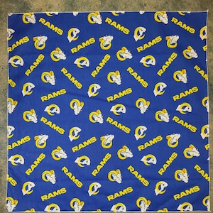 May include: A blue bandana with a repeated pattern of white ram heads and the word "RAMS" in yellow lettering.