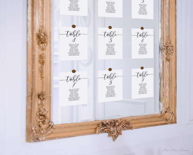 mirror wedding seating chart with table seating cards.  each card lists the table number and guest names. a gold wax seal attaches each card to the mirror.