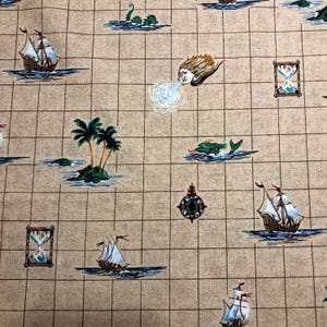 May include: Tan fabric with a grid pattern featuring nautical illustrations. The design includes sailing ships, palm trees on islands, sea monsters, hourglasses, and a wind-blowing face. The illustrations are in shades of blue, brown, and green.