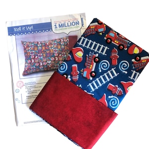 May include: A red and blue fabric pillowcase with a fire truck and ladder design. The pillowcase is rolled up and has a red backing. The text "Roll it Up!" and "1 MILLION PILLOWCASE CHALLENGE" is visible on the white paper behind the pillowcase.