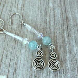 May include: Silver dangle earrings with a turquoise and clear crystal bead design. The earrings feature a silver spiral charm.
