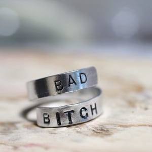 May include: Two silver rings with the words "BAD" and "BITCH" engraved on them.