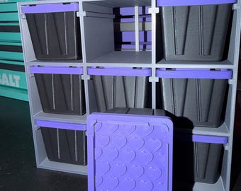 May include: A gray storage rack with nine compartments containing black bins with purple lids. One additional purple lid featuring a repeating embossed heart pattern is positioned in the foreground. The rack is placed in front of a purple Kobalt tool chest.