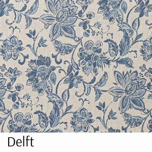 Puede incluir: Una tela con un patr&oacute;n floral repetitivo en tonos azules y blancos. El dise&ntilde;o presenta grandes flores y hojas estilizadas sobre un fondo neutro. La palabra "Delft" est&aacute; impresa en la parte inferior de la imagen.