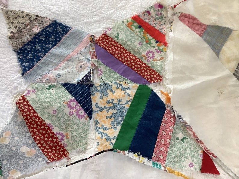 May include: Close-up of a handmade quilt with a starburst design. The quilt features various fabric patterns in shades of blue, red, green, and purple. The quilt is made of small fabric pieces sewn together, creating a unique and colorful textile.