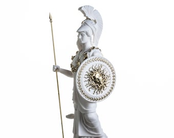 May include: A white statue of Athena, the Greek goddess of wisdom and warfare, holding a spear and shield. The shield features a gold sunburst design. The statue is detailed with a helmet and decorative elements, and the base reads "ATHENA".