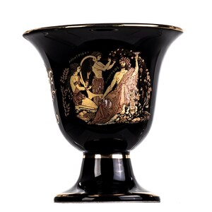 Może przedstawiać: Czarny ceramiczny wazon z pozłacanym wykończeniem i namalowaną na boku grecką sceną mitologiczną. Scena przedstawia trzy postaci, dwie kobiety i mężczyznę, z widocznym tekstem "AVANTIPAS" i "DIONYSOS".