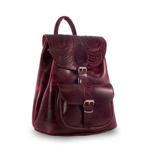 May include: A burgundy leather backpack with a front pocket and a buckle closure. The backpack has an embossed floral design.