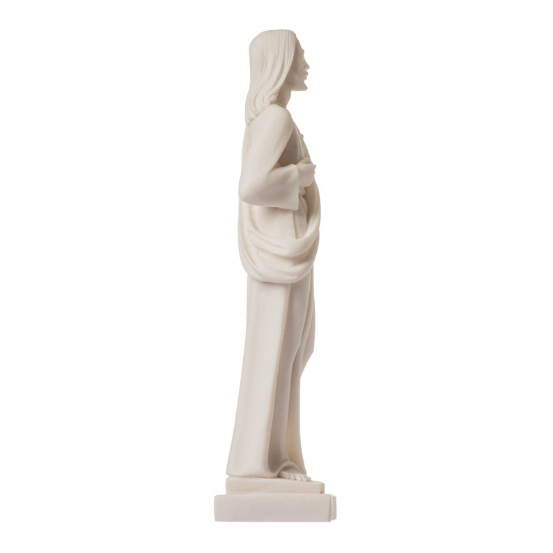 May include: White marble statue of a person standing with their hands clasped in front of them. The statue is wearing a long robe and has long hair. The statue is on a white base.