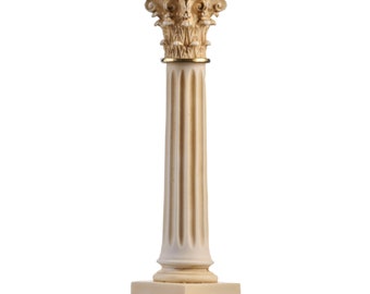 May include: A white decorative column with a fluted shaft and a detailed capital. The capital is adorned with intricate carvings and a gold band. The column stands on a square base.