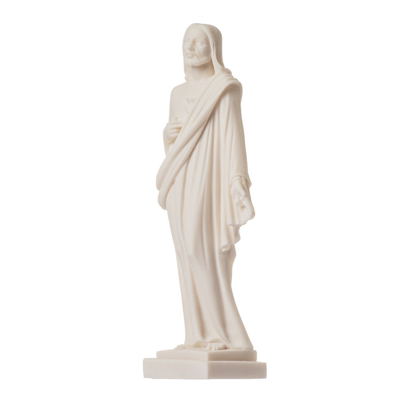 May include: White marble statue of Jesus Christ standing with his arms crossed and wearing a robe. The statue is on a white base.
