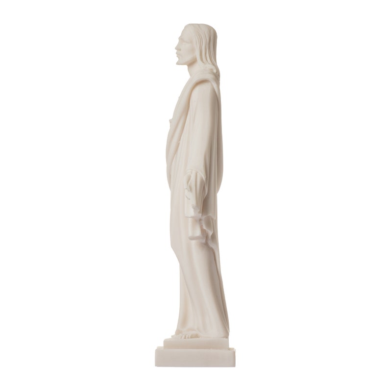May include: White marble statue of a person standing with their arms crossed and wearing a long robe. The statue is on a white base.