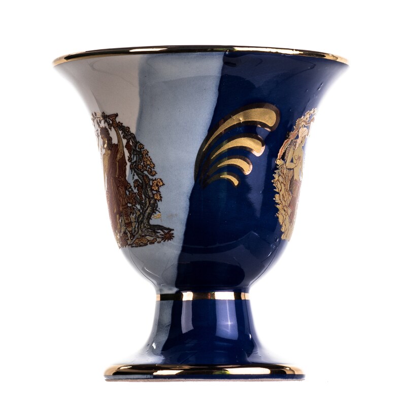 May include: A blue and white ceramic vase with gold accents and a decorative design. The vase has a wide mouth and a round base.