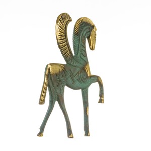 K&ouml;nnte beinhalten: Eine gr&uuml;ne und goldene gefl&uuml;gelte Pferdestatue. Das Pferd steht auf allen vieren, der Kopf ist zur Seite gedreht. Die Fl&uuml;gel sind hinter dem Pferd ausgebreitet.