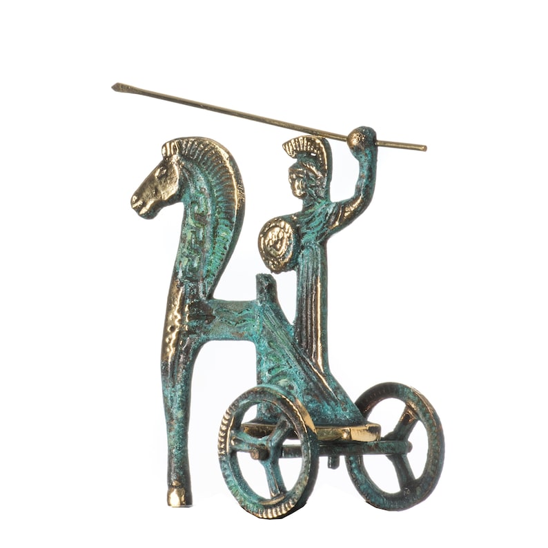 May include: A bronze-toned sculpture depicting a chariot pulled by a horse, with a figure holding a spear. The sculpture has a verdigris patina, with a spear extending from the figure's raised arm. The wheels of the chariot are visible.