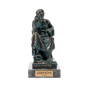 Könnte beinhalten: Eine Bronzestatue des griechischen Philosophen Sokrates, der auf einem Stuhl sitzt. Die Statue steht auf einem Marmorsockel mit der Inschrift "ΣΩΚΡΑΤΗΣ 410Π.Χ." in griechischer Sprache.