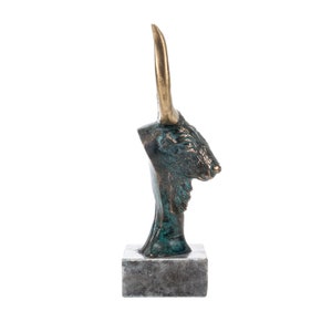May include: Bronze sculpture of a bull's head with gold horns on a gray marble base.