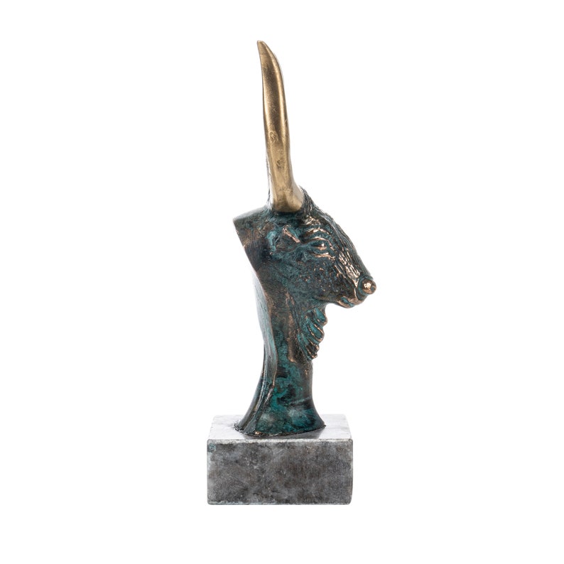 May include: Bronze sculpture of a bull's head with gold horns on a gray marble base.