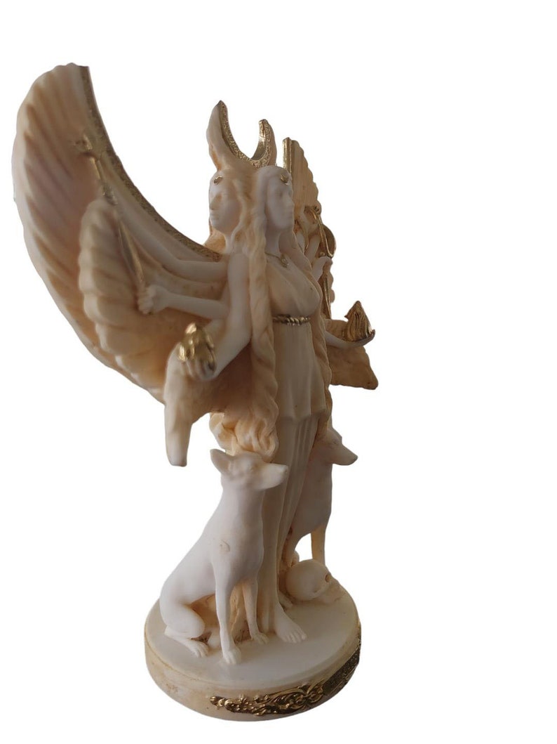 May include: White marble statue of a triple goddess with wings, holding a staff and a crescent moon. The goddess is standing on a base with two dogs at her feet.