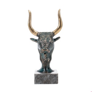 May include: A bronze bull head sculpture with gold horns on a gray marble base.