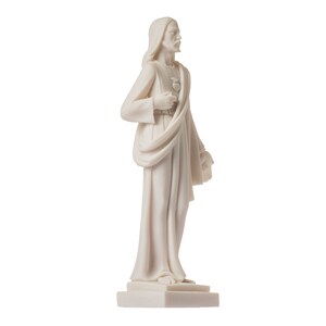 May include: White marble statue of Jesus Christ with a heart in his hand, standing on a white base.
