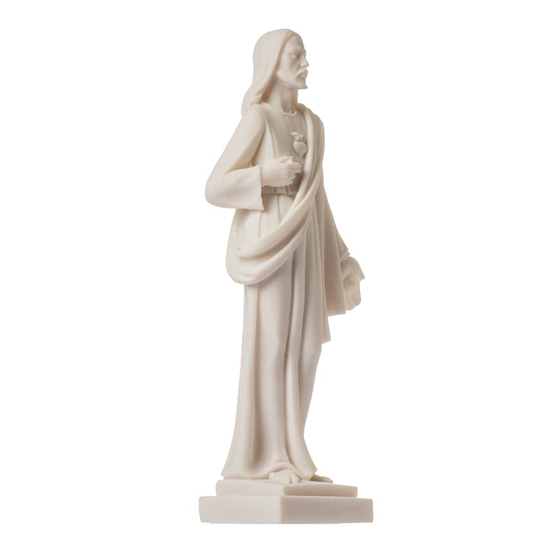 May include: White marble statue of Jesus Christ with a heart in his hand, standing on a white base.