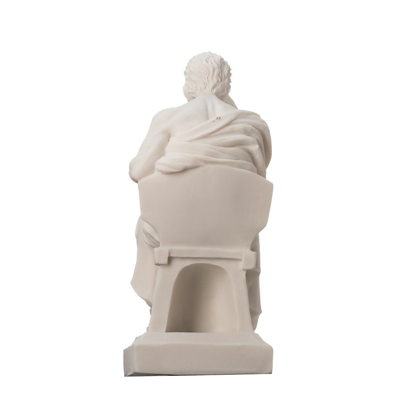 May include: White marble statue of a seated figure, the figure is facing away from the viewer, the statue is on a white base.