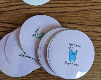 May include: A stack of pink round stickers with the text "Hydrate or Die-drate" and a cartoon illustration of a glass of water.
