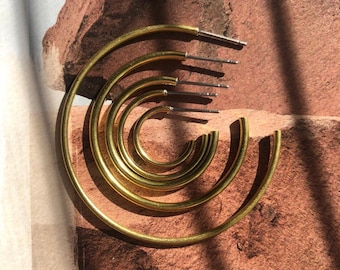 May include: Set of five gold hoop earrings of varying sizes. The hoops are made of a thick, smooth metal and have a polished finish.