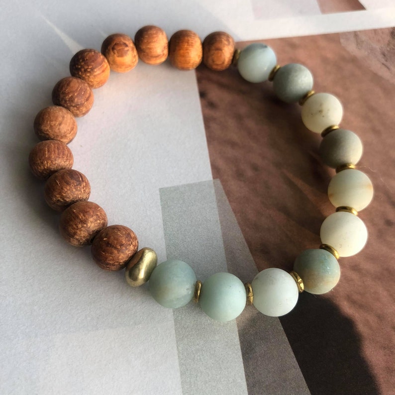 May include: A beaded bracelet with brown wooden beads and light green beads separated by gold spacers.