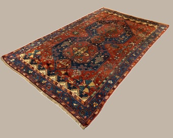 May include: A traditional Persian rug with a red, blue, and cream color scheme. The rug features intricate geometric patterns and a central medallion.