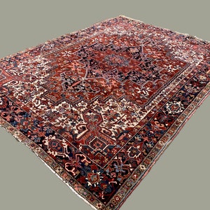 May include: A traditional Persian rug with a red, blue, and white geometric pattern. The rug has a central medallion and a border with intricate details.