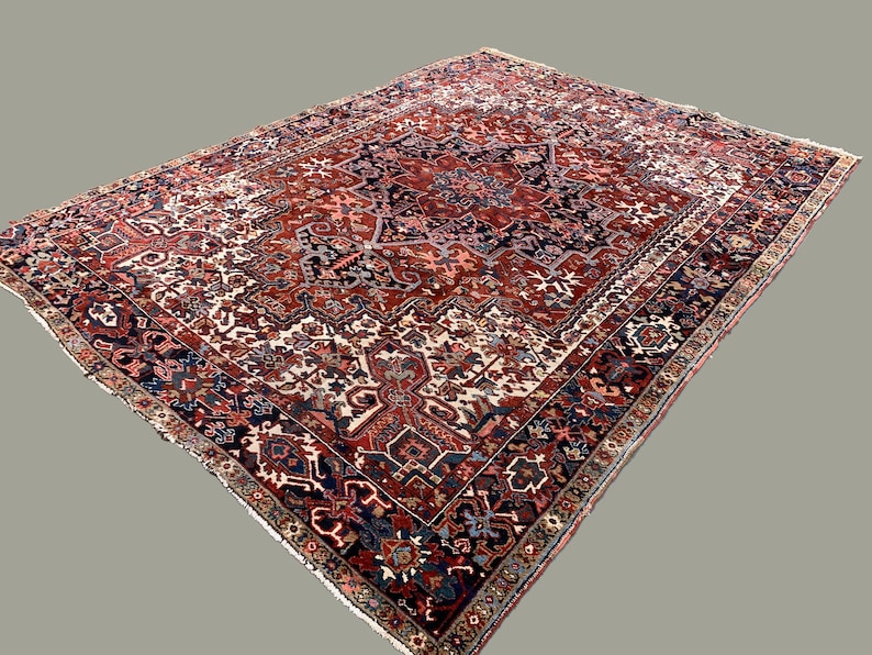 May include: A traditional Persian rug with a red, blue, and white geometric pattern. The rug has a central medallion and a border with intricate details.